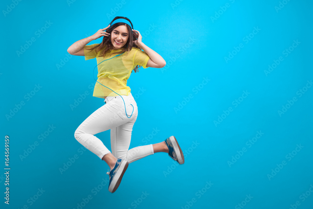 Smiling brunette girl in headphones jumping