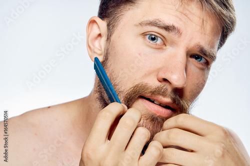 Young guy with a beard on a white isolated background combing out