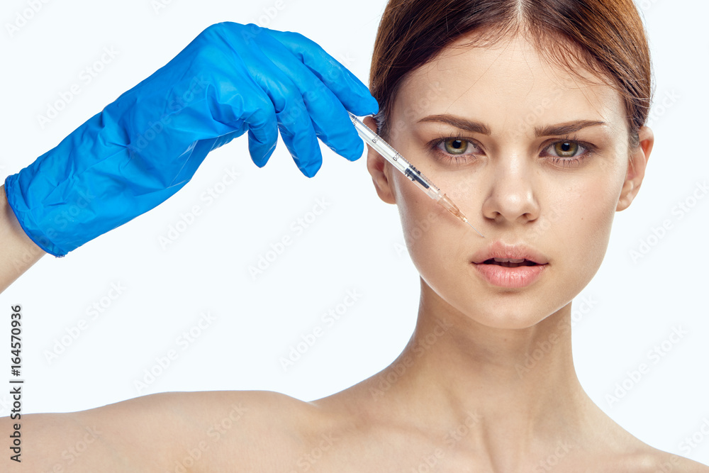 Young beautiful woman on white isolated background holds a syringe, plastic surgery, medicine