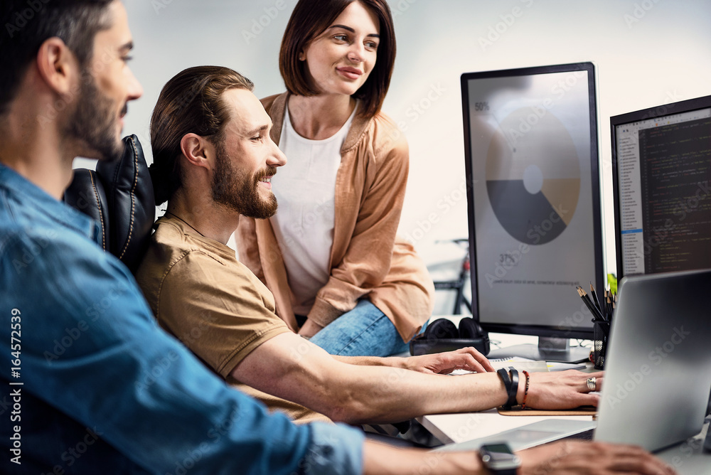 Outgoing bearded worker showing data to colleagues Outgoing bearded worker showing data to colleagues