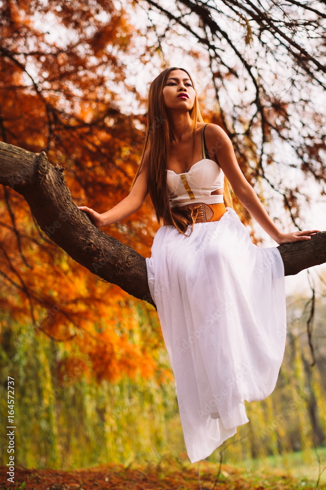 Fantastic young woman. beautiful fantasy girl fairy with white long dress in windy autumn park Fantastic young woman. beautiful fantasy girl fairy with white long dress in windy autumn park