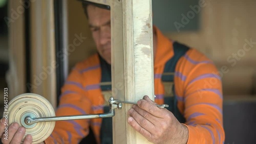 A woodworker is using the wrench to adjust a car mirror a bit. He is designing a barnd new vintage wooden car.  photo