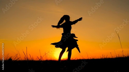 Silhouette of young witch dancing at field