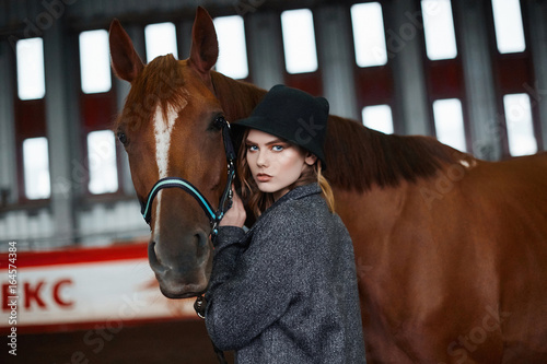 Beautiful girl in hat walking with a horse