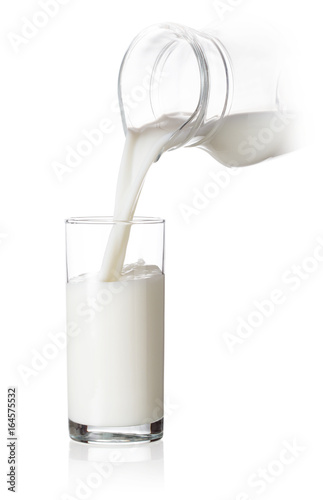 Glass filled with milk pouring from a jug