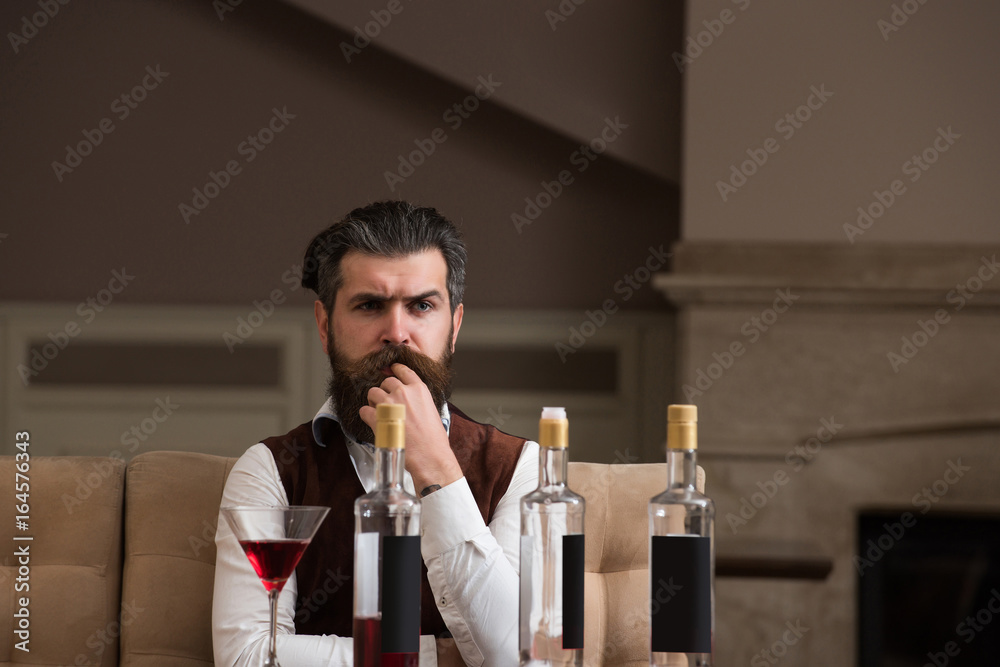 Obraz premium Hipster sitting at table with three bottles and glass