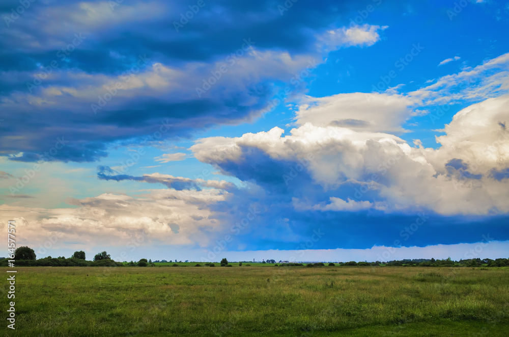 Beautiful clouds in blue sky and field in countryside. Summer rural landscape.