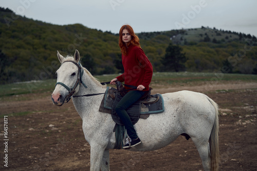Young beautiful woman walking in the mountains with her horse