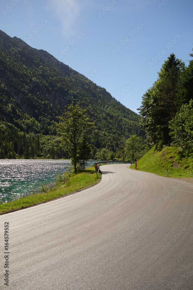 kurvige Straße mit See in den Alpen