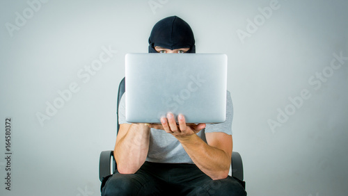 Wallpaper Mural Ein maskierter Hacker mit dem Laptop in der Hand versucht wichtige Informationen / Daten zu finden Torontodigital.ca