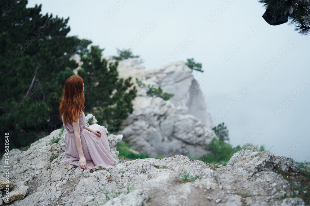 Young beautiful woman on a cliff of a mountain near the sea