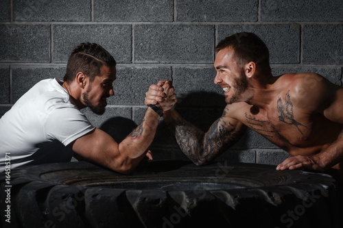 Two men with hands clasped in arm wrestling challenge. Bodybuilding concept