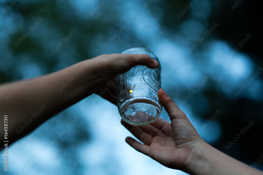Children holding jar with firefly inside, close-up Children holding jar with firefly inside, close-up