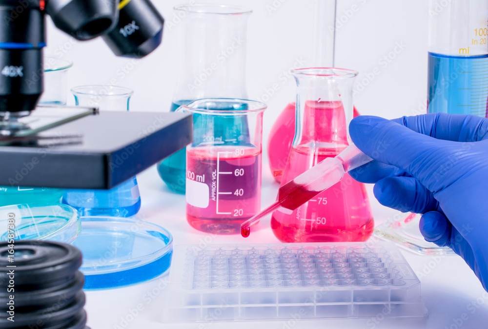 scientist pipetting chemical liquid into 96 well micro plate. examining samples in laboratory and close up of microscope . laboratory science, clinic and research concept.