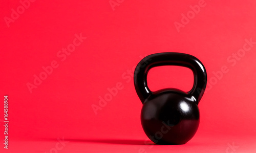 Fototapeta Naklejka Na Ścianę i Meble -  Black cast iron kettlebell on a red background