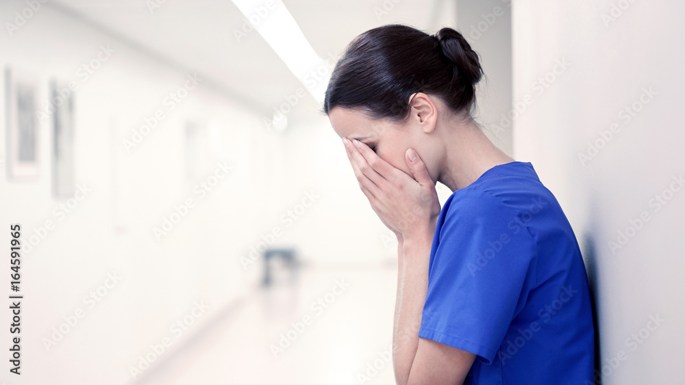 sad or crying female nurse at hospital corridor sad or crying female nurse at hospital corridor