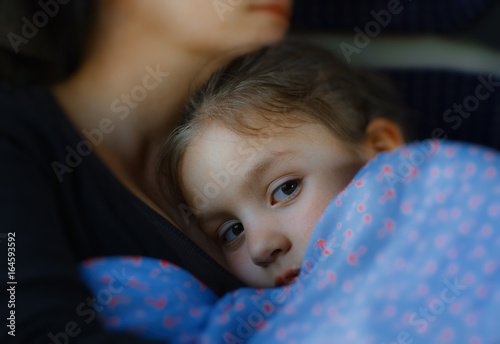 Little girl trying to sleep in her mother's arms