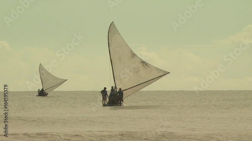 Wide shot of two sailboats getting closer to deep sea and father away from land