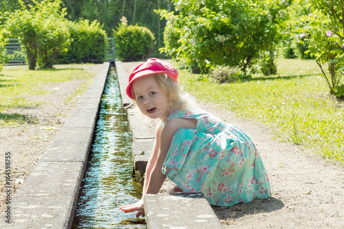 Little girl playing with water in a creek on a hot sunny day