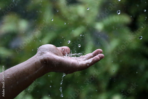 Picture of rain drops on hand. Hands extended in the rain. Human hands in the rain.Photo with bokeh and blur background.
