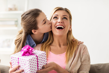 girl giving birthday present to mother at home