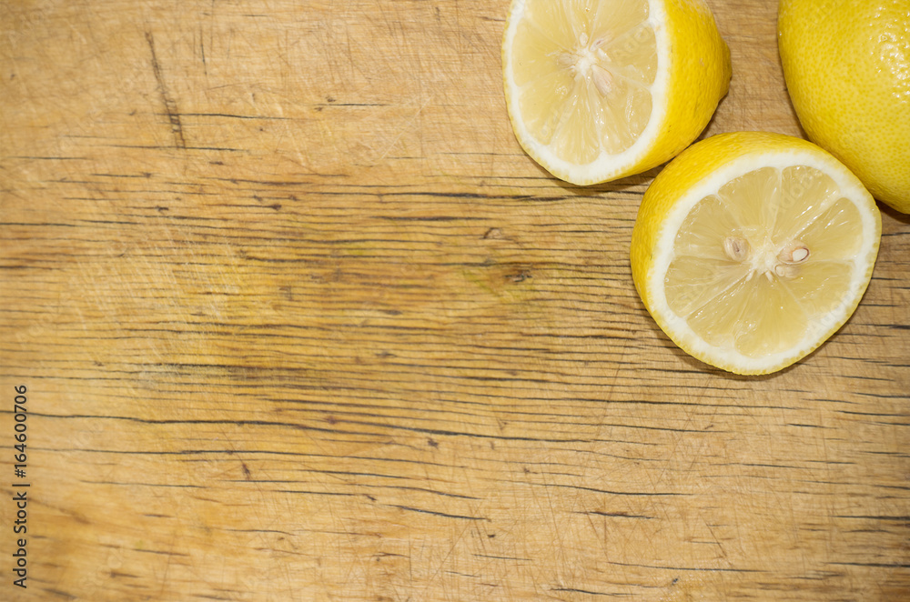 Yellow fresh lemon and two half of lemon on the wooden cutting board Yellow fresh lemon and two half of lemon on the wooden cutting board