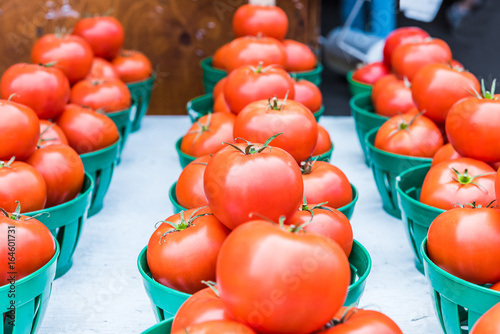 Closeup of red ripe tomatoes with green stems in baskets in farmers market photo