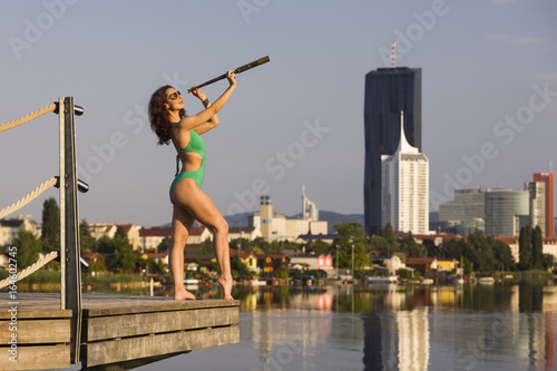 Girl in green swimsuit looking through monocular