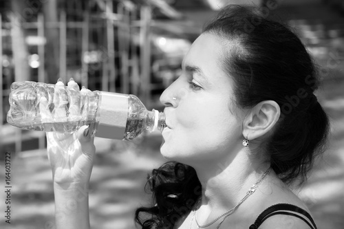 Young woman drinking water after run photo