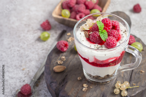 glass with raspberries, granola and yogurt arranged in layers