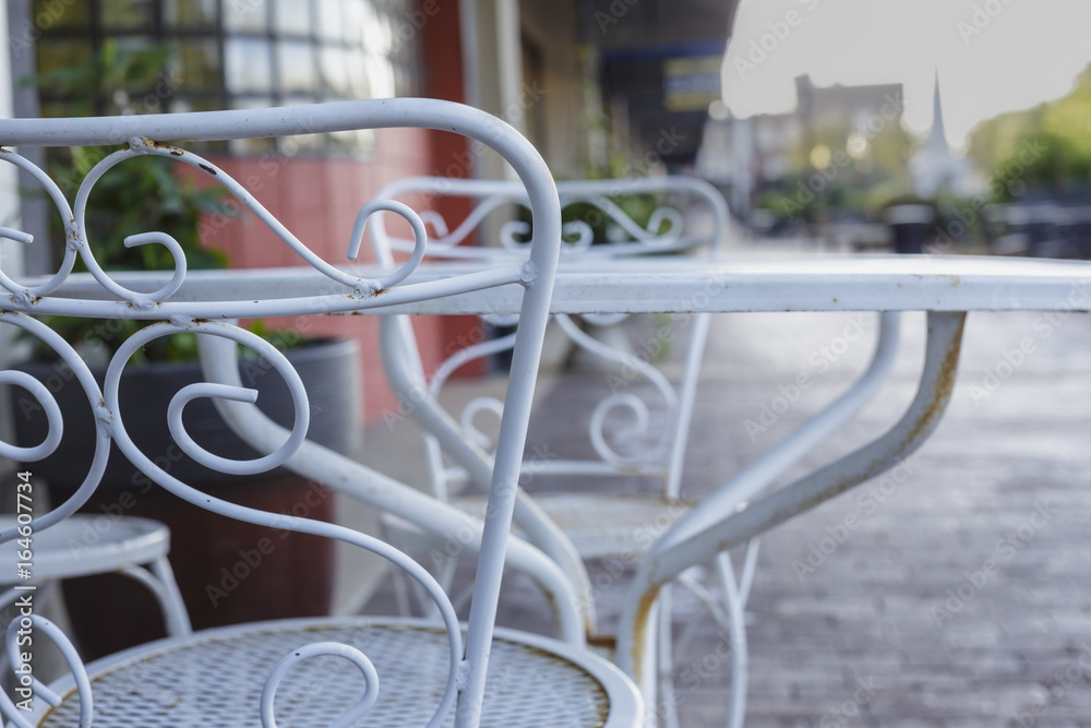 white metal table and chairs outside a shop on a city sidewalk white metal table and chairs outside a shop on a city sidewalk