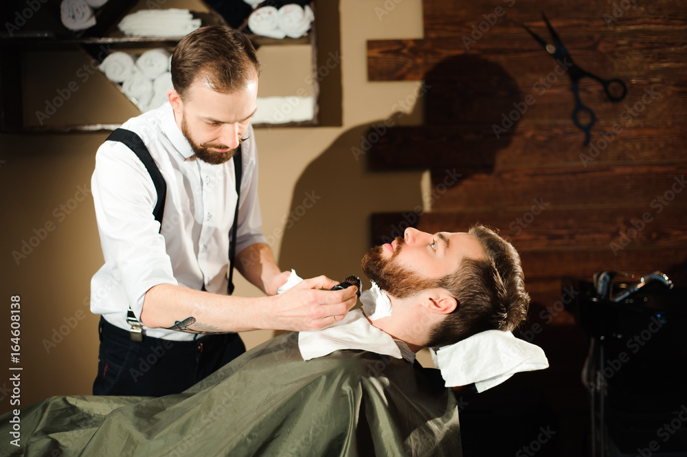 Fototapeta premium Master cuts hair and beard of men in the barbershop