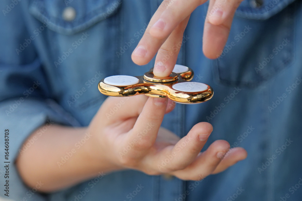 Gold fidget spinner in hand. Popular trendy toy close-up.