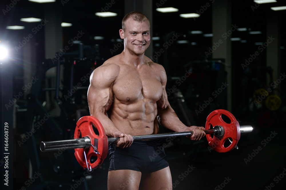 Caucasian handsome fitness model training in the gym. Man on diet flexing muscles