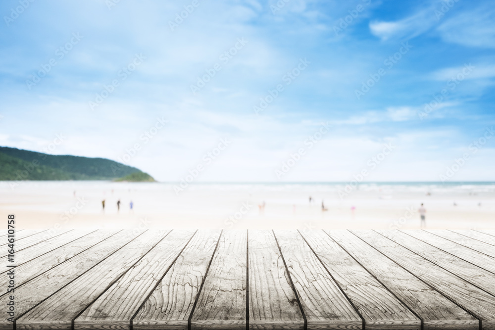 Empty wooden table with party on beach blurred background in summer time.