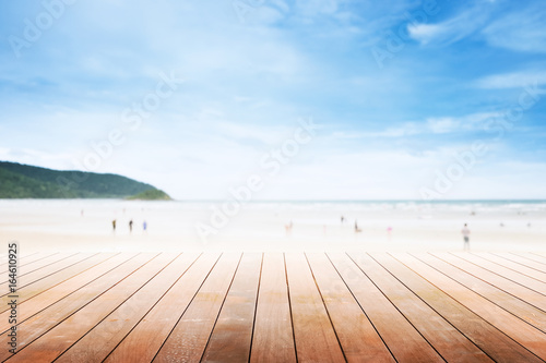 Empty wooden table with party on beach blurred background in summer time.