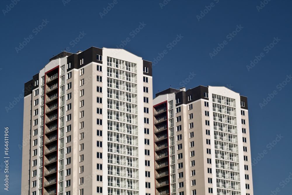 Two residential buildings in front of blue sky.