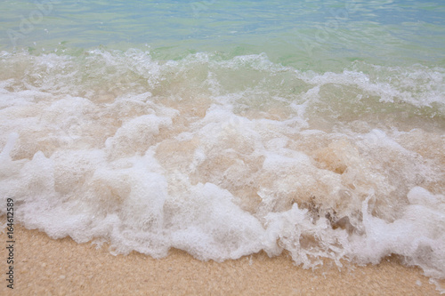 Abstract blurry background of soft wave of blue sea with sandy beach.