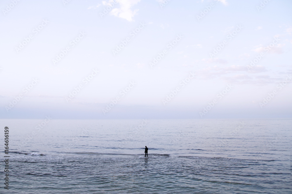 Hombre vestido con traje andando en solitario por el agua del mar