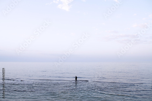 Hombre vestido con traje andando en solitario por el agua del mar © ikuday