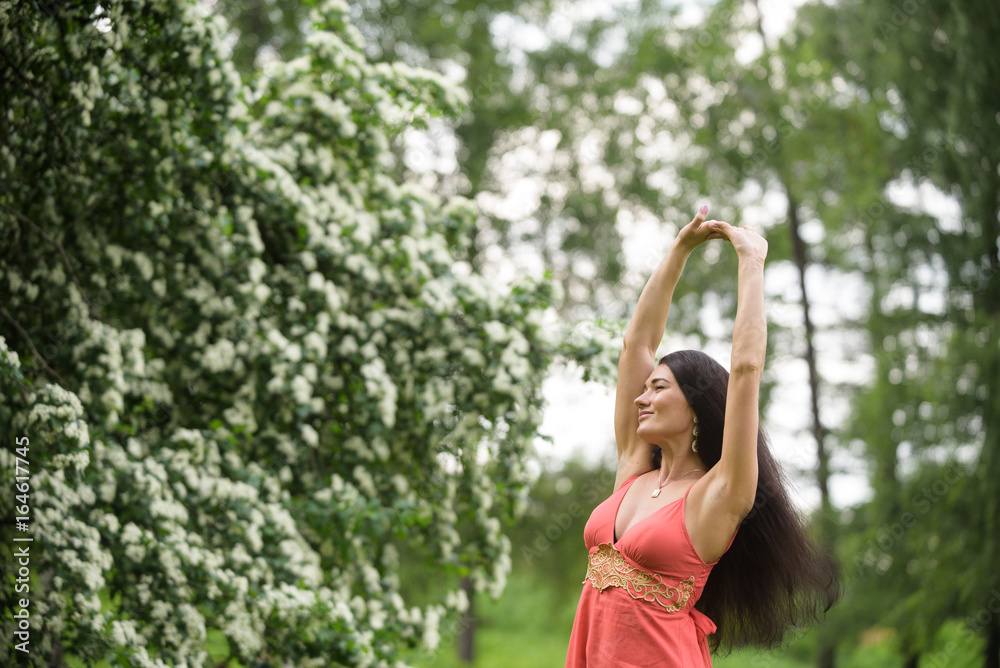 Happy girl stretching herself in park near blossoming tree Happy girl stretching herself in park near blossoming tree