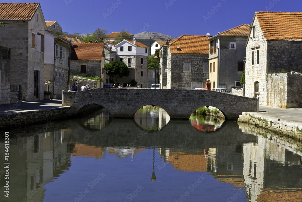 Unidentifiable tourists on the old bridge in the 15th century village of Vrboska, in Croatia