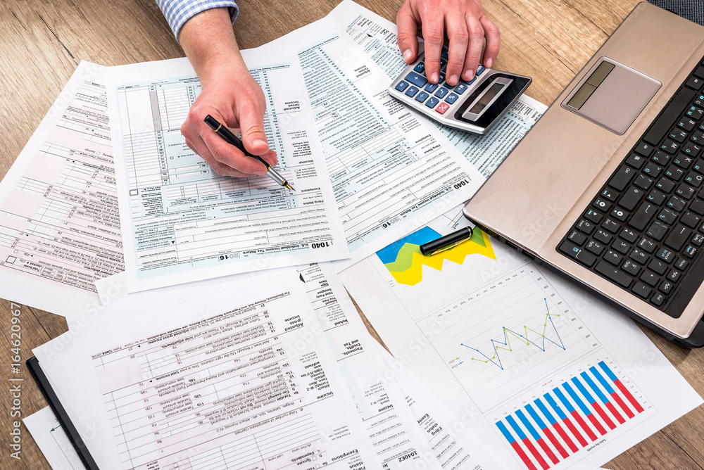 man filling tax form with business report, chart, laptop man filling tax form with business report, chart, laptop
