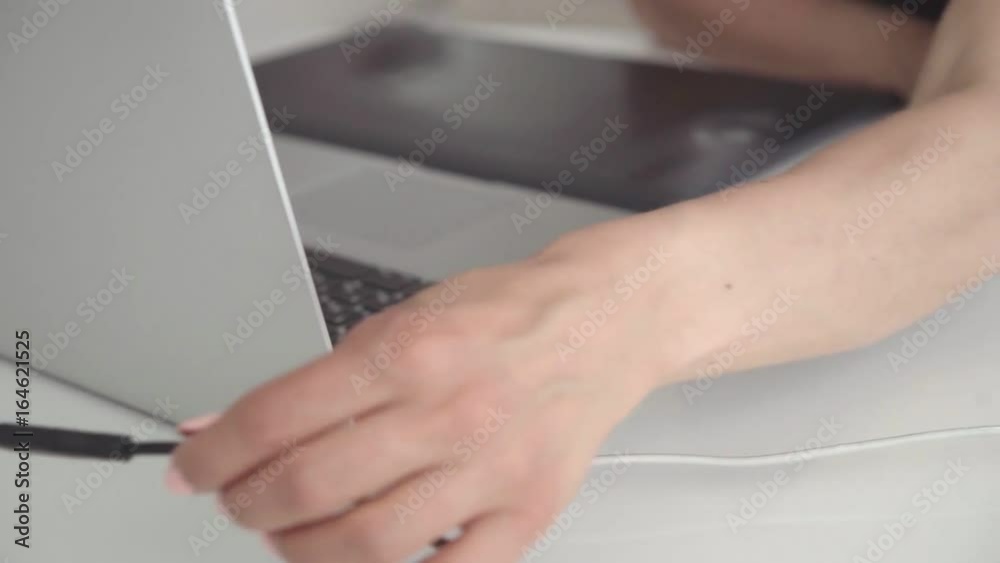 Female hand using graphics tablet on table close up. Woman working with laptop in office Female hand using graphics tablet on table close up. Woman working with laptop in office