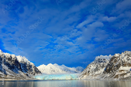 White snowy mountain, blue glacier Svalbard, Norway. Ice in ocean. Iceberg in North pole. Blue sky with ice floe. Beautiful landscape. Cold sea water. Land of ice. Cold Winter Arctic. Travel in ocean