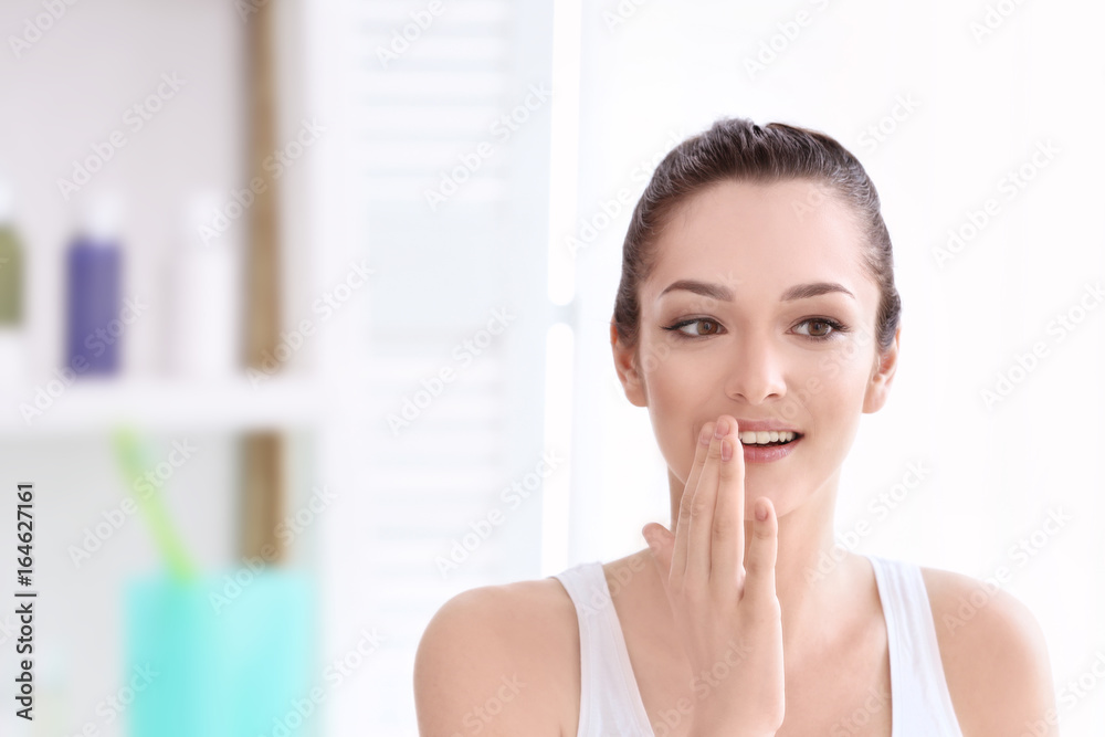 Young woman touching lips in light room Young woman touching lips in light room