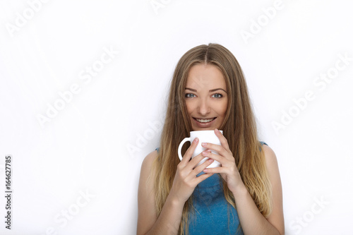 Headshot of young adorable playful blonde woman with cute smile in cobalt color blouse posing with big pure white mug on white backdrop