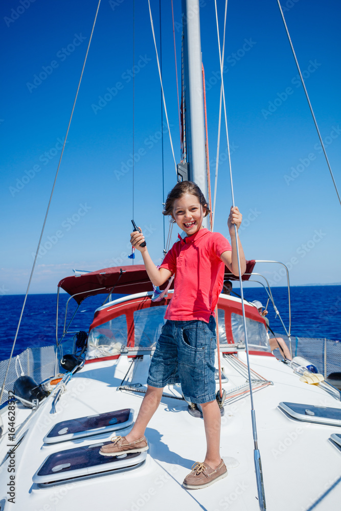 Little boy on board of sailing yacht on summer cruise. Travel adventure, yachting with child on family vacation. Little boy on board of sailing yacht on summer cruise. Travel adventure, yachting with child on family vacation.