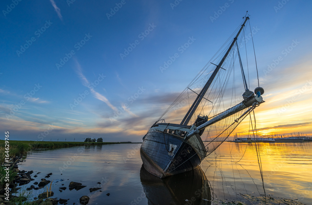 Scenic sunset at a stranded sailing boat near Lemmer, the Netherlands