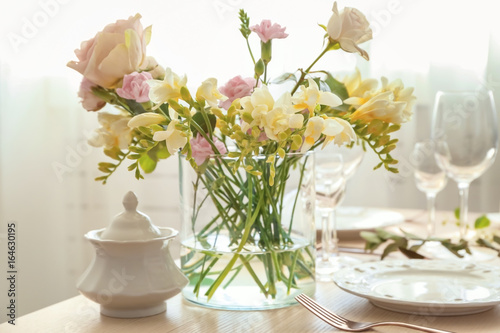 Beautiful bouquet of fresh freesia in vase on table